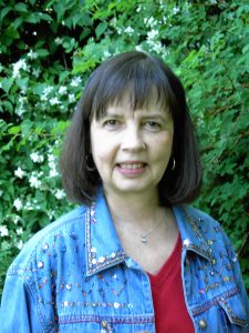 Paula Wild standing against a backdrop of green growth.